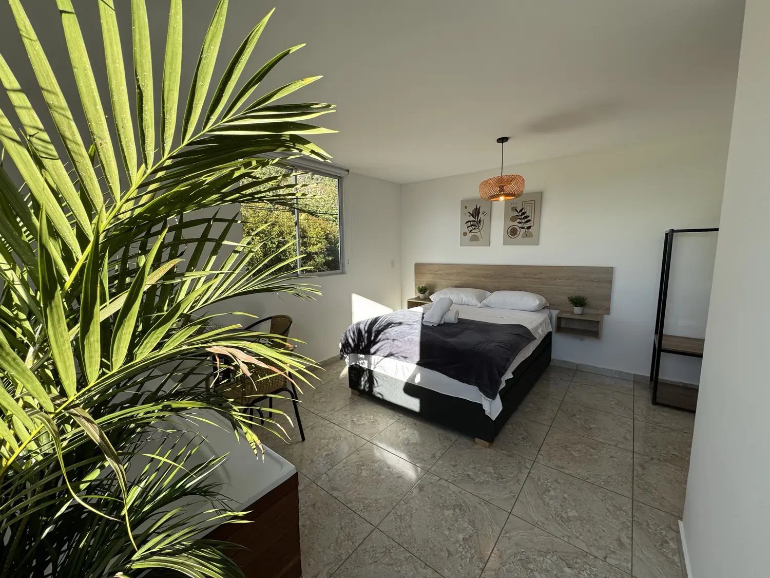 Habitación Caoba con cama doble, plantas y ventana al verde.