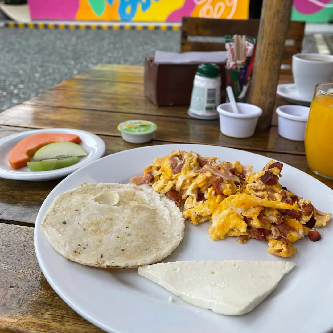 Plato de desayuno con arepa, huevos y café.