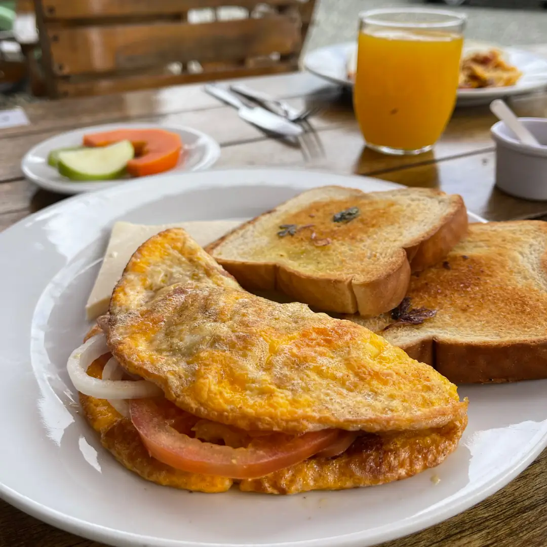 Desayuno servido en el restaurante del hotel: huevos, tostadas, fruta y jugo.