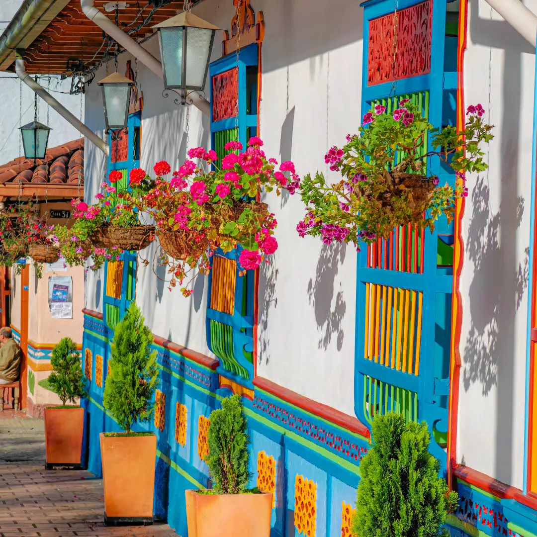 Calle de Guatapé con fachadas de colores, flores y zócalos pintados.