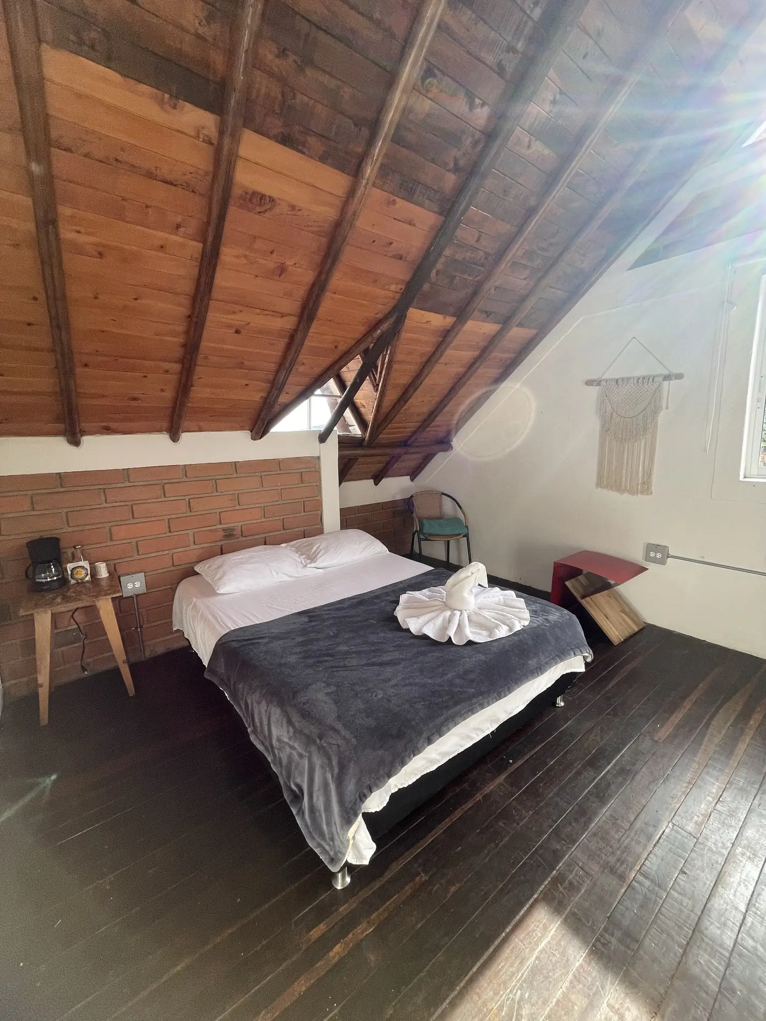 Habitación Laurel con techo de madera a dos aguas y cama doble.