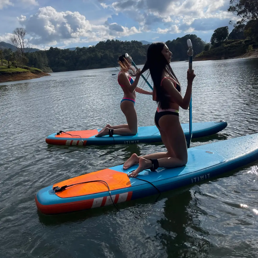 Huésped de pie sobre una tabla de paddle en el agua del embalse.