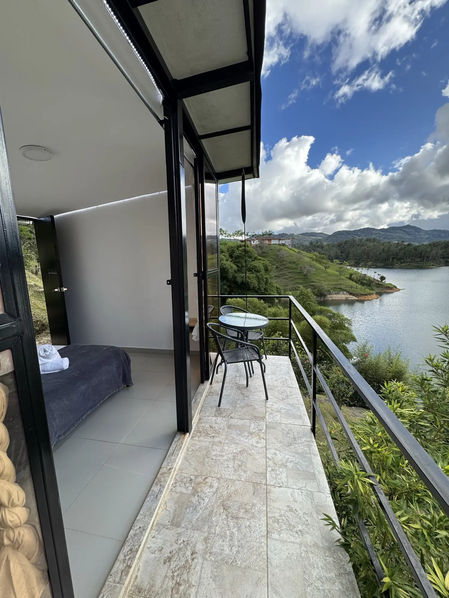 Cabaña Roble Deluxe con ventanales de piso a techo y balcón tipo deck sobre el embalse.