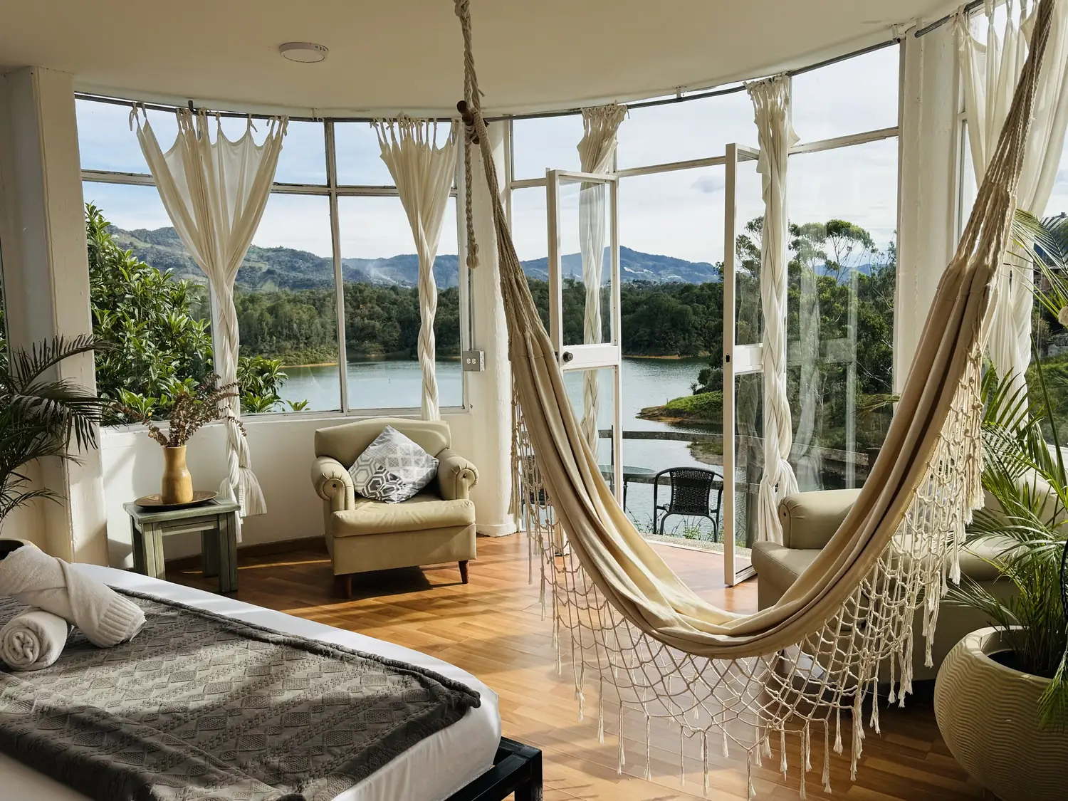 Suite La Madriguera con cama King, hamaca y ventanales curvos sobre el embalse.